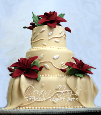 Ivory Fondant Wedding cake with pearled fondant accents fondant drapes and adorned with burgundy Sugar lilies.