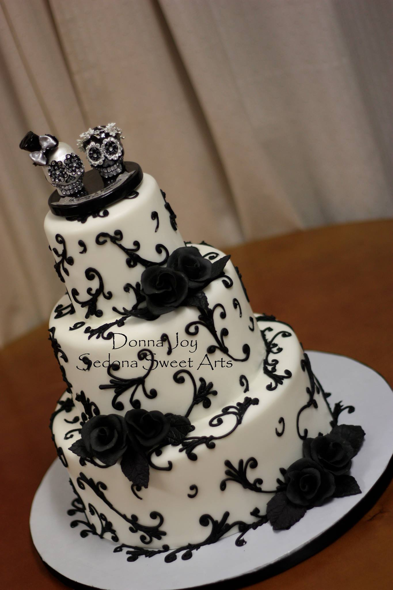 Day of the Dead wedding cake. Black swirls black sugar roses adorned with a Day of Dead cake topper